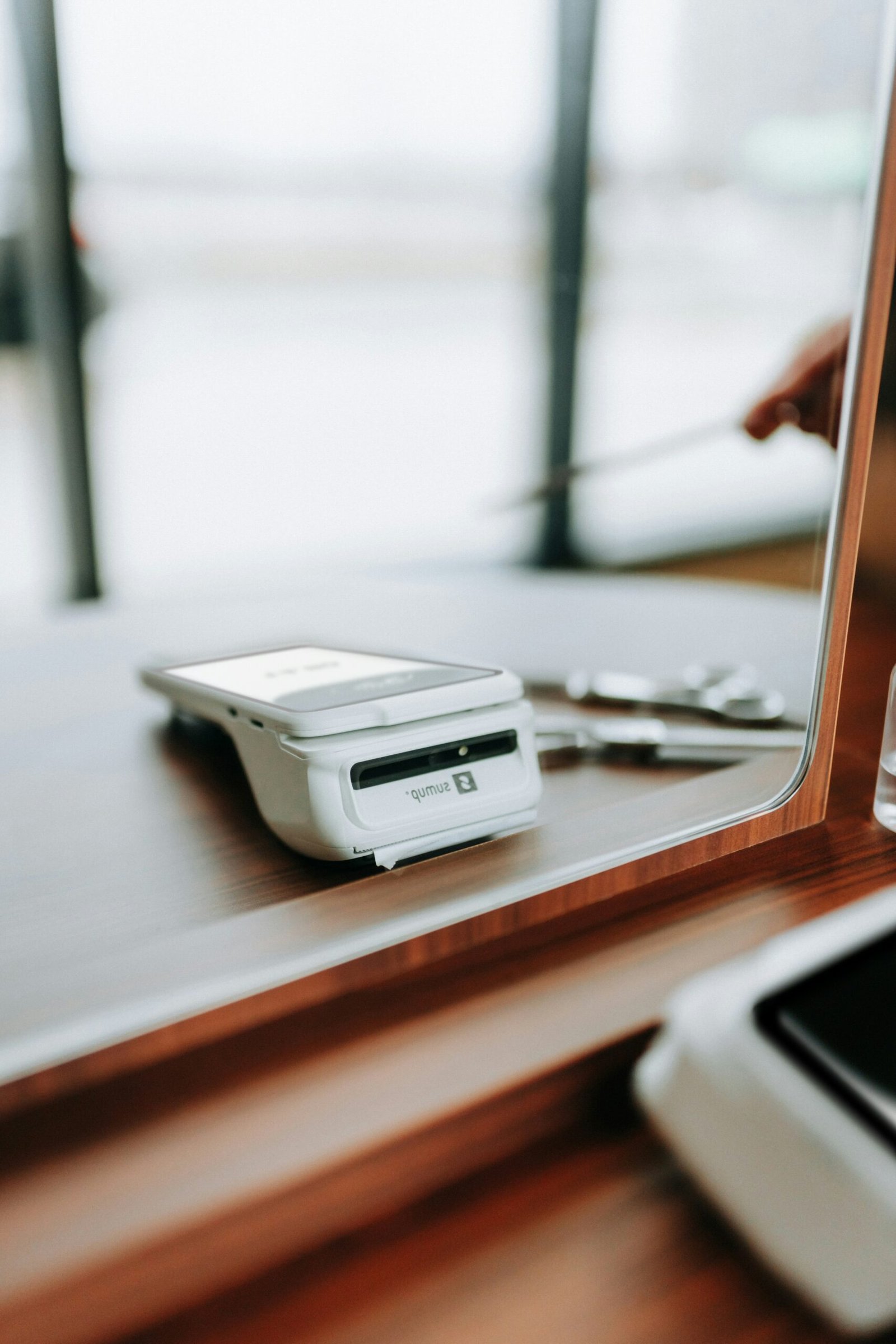 A credit card reader sits on a wooden table.