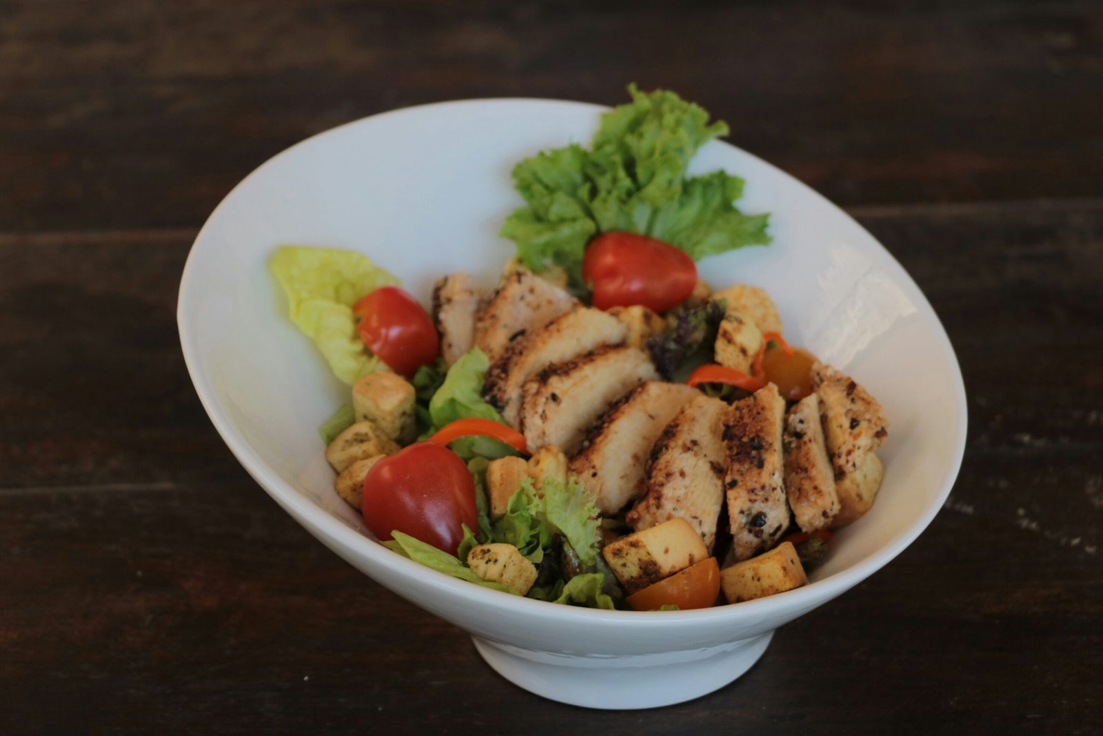 A white bowl filled with meat and vegetables